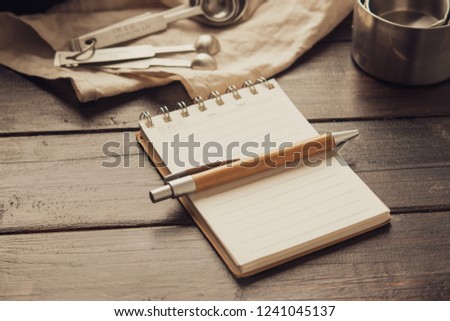 Empty white space notebook with pen and pastry bakery tools on wooden background. Retro vintage tone filter effect, selective focus. Home baking concept.