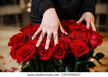 Romantic proposal, wedding or Valentine's Day scene. Woman hand with engagement ring with resd roses on background.