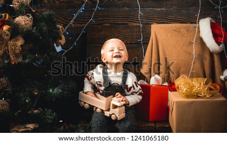 Cute little child opening present near Christmas tree. Merry Christmas and Happy New Year. The child boy laughing and enjoying the gift. Christmas dream.