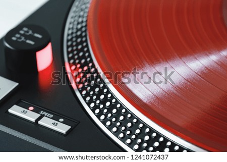 Vinyl record closeup. A ray of light on a piece of vinyl. Turntable player. Sound technology for DJ to mix and play music. Red vinyl. The texture of the bands on the vinyl record. Turntable player
