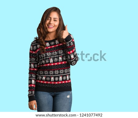 Full body young woman wearing a christmas jersey smiling and raising thumb up