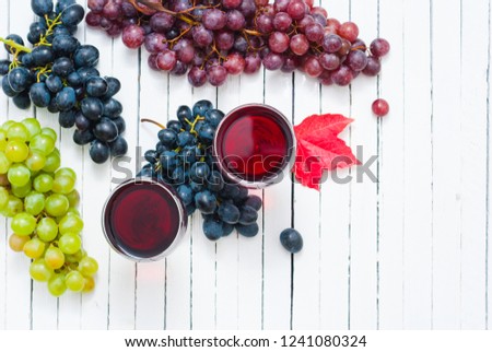 two glasses of red wine and grapes on white wooden table background