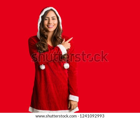 Full body young santa curvy woman smiling and pointing to the side