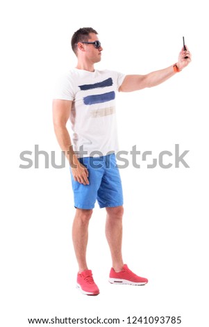Young casual man in summer clothes photographing with mobile phone. Full body isolated on white background. 