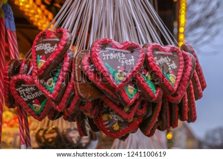 Several gingerbread hearts with happy holiday in German at a Christmas market