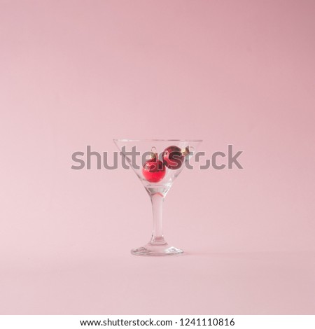 Christmas tree decoration in martini glass on pastel pink background with creative copy space. New year or Christmas eve party concept.
