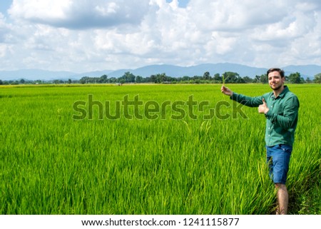 Wheat land man looking forward on farm plantation with mountains on background