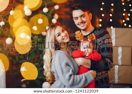 Beautiful family standing near Christmas tree. Cute mother in a gray sweater. Little boy with handsome father
