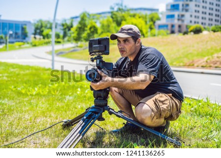 a professional cameraman prepares a camera and a tripod before shooting