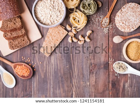 Different types of high carbohydrate food. Flour, bread, dry pasta and lentils and other ingredients on the wooden table. Royalty-Free Stock Photo #1241154181