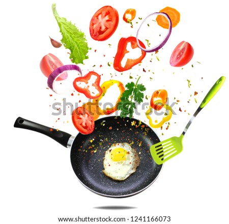 Healthy eating and cooking with various flying chopped vegetables ingredients, fried egg pan isolated on white background, front view. Concept diet and healthy eating.