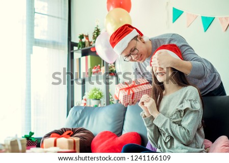 Christmas Gift. Asian Couple in Santa's Hat with Christmas and New Year Gift at Home.