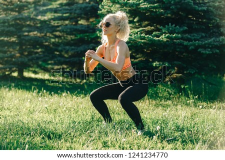 Photo of young curly-haired sports woman practicing yoga on rug 