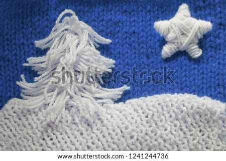 Hadmade Christmas tree and star on blue knitted woolen background with copy space for text Christmas concept