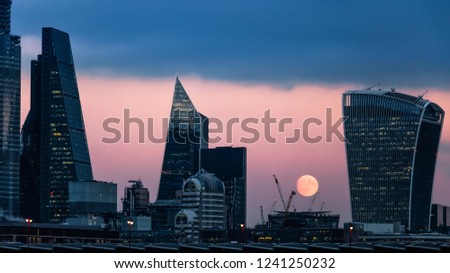 Skyscrapers in the City of London financial district after sunset with full moon in the background of the construction area with cranes, London, United Kingdom