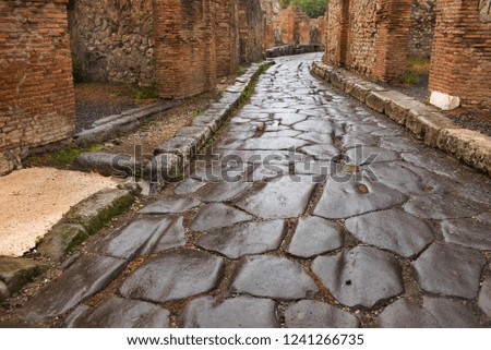 wet stone road between buildings in in Pompei in Italy