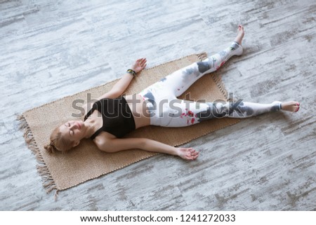 Adult woman meditating in savasana pose on bamboo yoga mat after working out at home and doing yoga exercise. Shavasana Posture, meditation, resting after practice, breathing. Top view Royalty-Free Stock Photo #1241272033