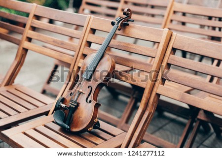 Shot of violin on wooden chair, with no people. Classic music and art concept. Symphony. Horizontal outdoor shot