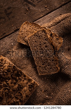 Whole grain bread put on kitchen wood old table. Fresh bread close-up. Slices of homemade bread on juta bag and industrial wooden background. The healthy eating and traditional bakery concept.