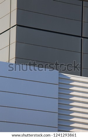 Close up outdoor view of parts of building facades with rectangular shapes. Modern design with rectangles and black lines. New architecture made of grey steel panels. Bright gray colored surfaces.