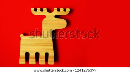 wooden deer sign, symbol - christmas toy on red paper background. happy new year and merry christmas                   