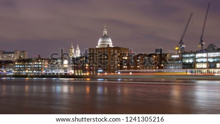 City of London at night as seen from the South bank with boat light trails in the river