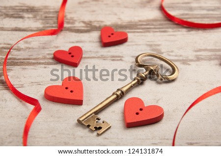 red wooden hearts on wooden board with key