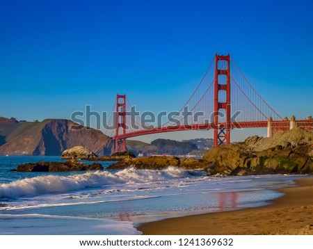 Waves rolling in a the Golden Gate Bridge on Baker Beach just before sunset