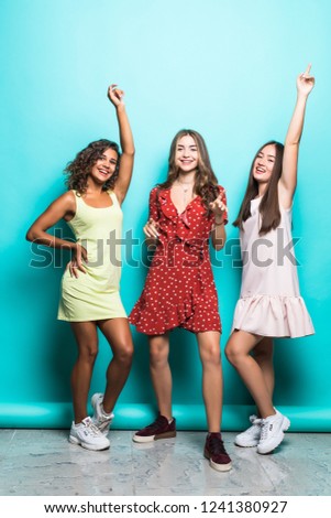 Joyful tanned european girl posing with pleasure during rest with friends. Funny african young woman dancing in studio enjoying free time with university friends.