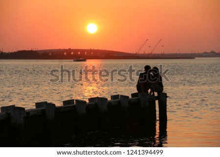 sunset pictures with silhouette couple kissing on a dock 