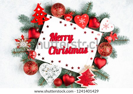 Christmas photoframe surrounded by branches of a New Year tree, red Christmas decorations with copy space. Top view, flat lay. Merry christmas text