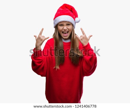 Young beautiful girl wearing christmas hat over isolated background shouting with crazy expression doing rock symbol with hands up. Music star. Heavy concept.