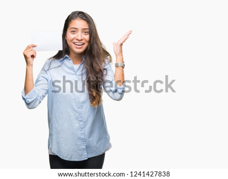 Young arab woman holding blank card over isolated background very happy and excited, winner expression celebrating victory screaming with big smile and raised hands