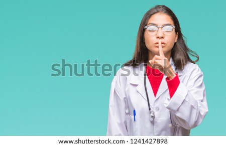 Young arab doctor woman over isolated background asking to be quiet with finger on lips. Silence and secret concept.