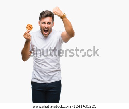 Young handsome man eating a sweet waffle over isolated background annoyed and frustrated shouting with anger, crazy and yelling with raised hand, anger concept