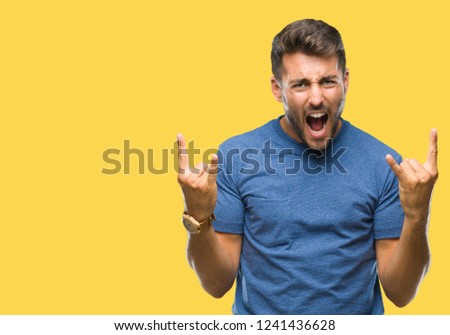 Young handsome man over isolated background shouting with crazy expression doing rock symbol with hands up. Music star. Heavy concept.