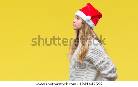Young beautiful blonde woman wearing christmas hat over isolated background looking to side, relax profile pose with natural face with confident smile.