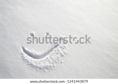 Face happy smiley drawn on white snow, frosty winter day. Close-up. Royalty-Free Stock Photo #1241443879