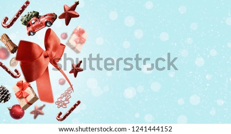 Colorful Christmas ornaments and presents falling over the side of blue background, covered with snowflakes with empty space