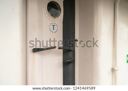 A closed door with a porthole on a ship.