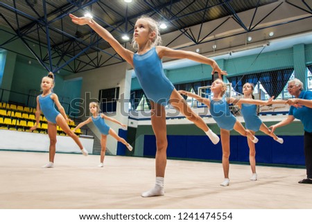 Group of  happy children doing exercise in gym with trainer