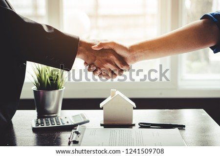 The homeowner is happy after receiving the transfer of the right to occupy the home. Agent and client shaking hands after signed document and done business deal for transfer right of property. Royalty-Free Stock Photo #1241509708