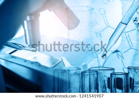 microscope and dropping chemical liquid to test tubes with lab glassware, science laboratory research and development concept in blue tone.