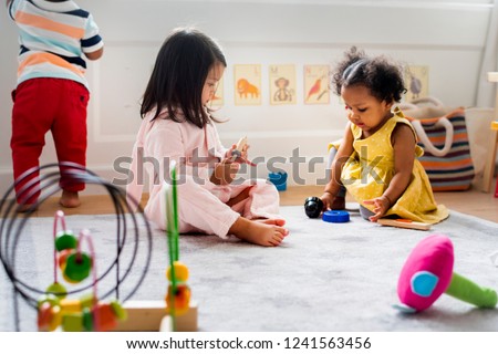 Little kids playing toys in the playroom Royalty-Free Stock Photo #1241563456