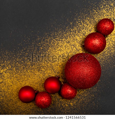 Christmas background. Red Christmas balls of different sizes and gold glitter on a black textural background. With free space for your text.