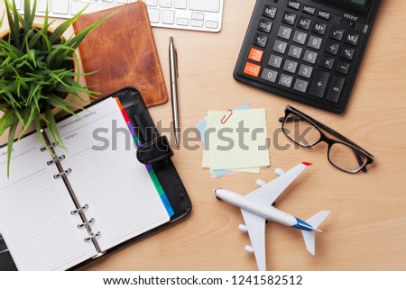 Business trip concept. Accessories on desk table. Pc keyboard, passport, notepad, calendar and airplane toy. Top view with copy space