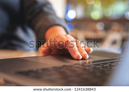 Closeup image of hands using and touching on laptop touchpad on wooden table
