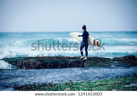 Woman surfer with surfboard going to surf the big waves