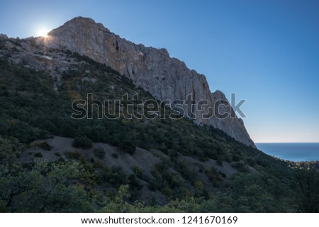 The sun looks out from behind the mountain Falcon near the Novy Svet village