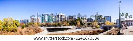 Panoramic view of San Jose's downtown skyline as seen from the shoreline of Guadalupe river on a sunny fall day; Silicon Valley, California